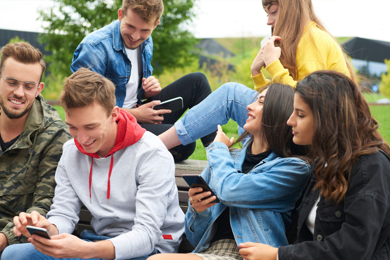 Jugendliche Gruppe sitzt zusammen und schaut auf Smartphones