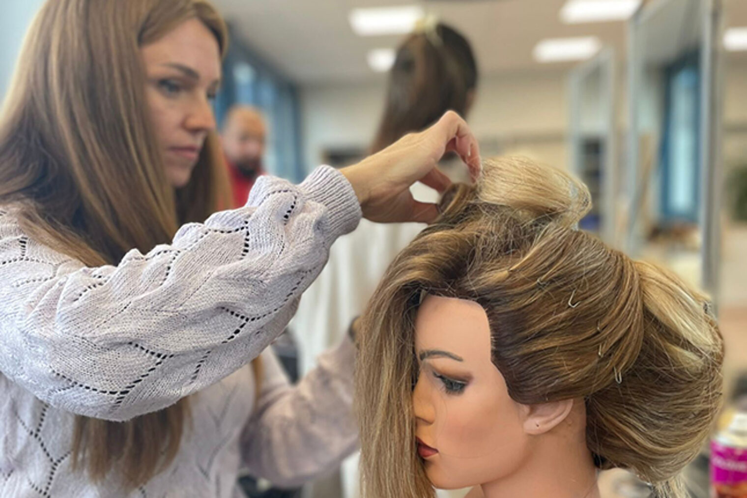 Teilnehmerin des Meisterkurses Friseure in Aschaffenburg bei ersten Steckversuchen zur Steckfrisur mit Haarteilen