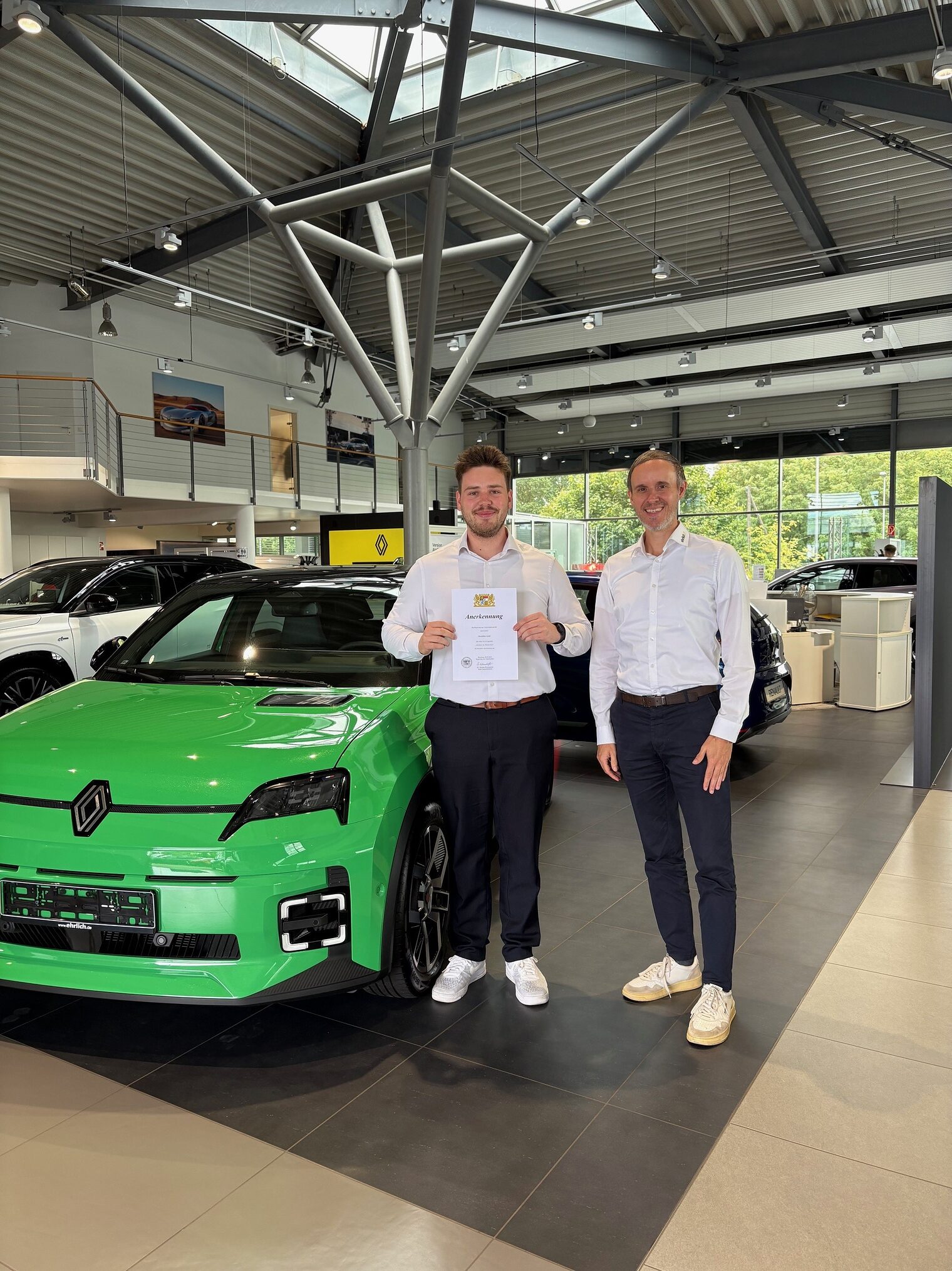 Zwei Männer stehen im Autohaus vor einem grünen Wagen
