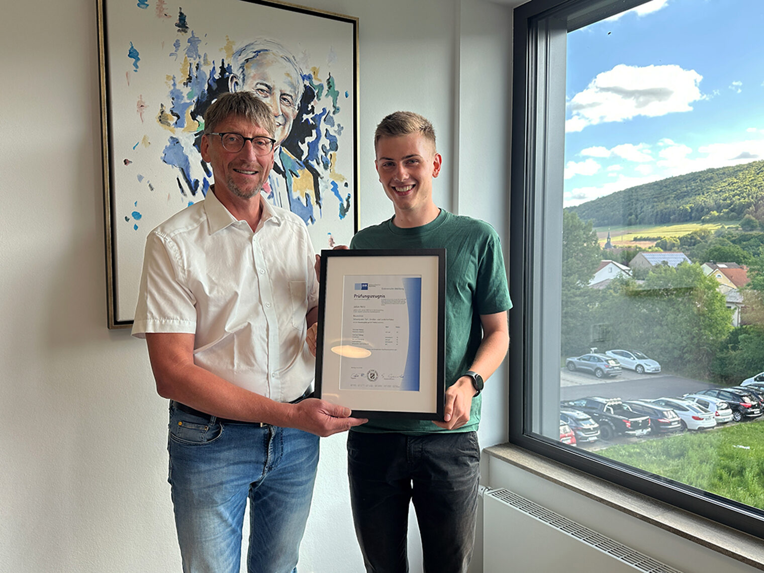 Zwei Personen halten eine Ehrung in der Hand. Bauzeichner