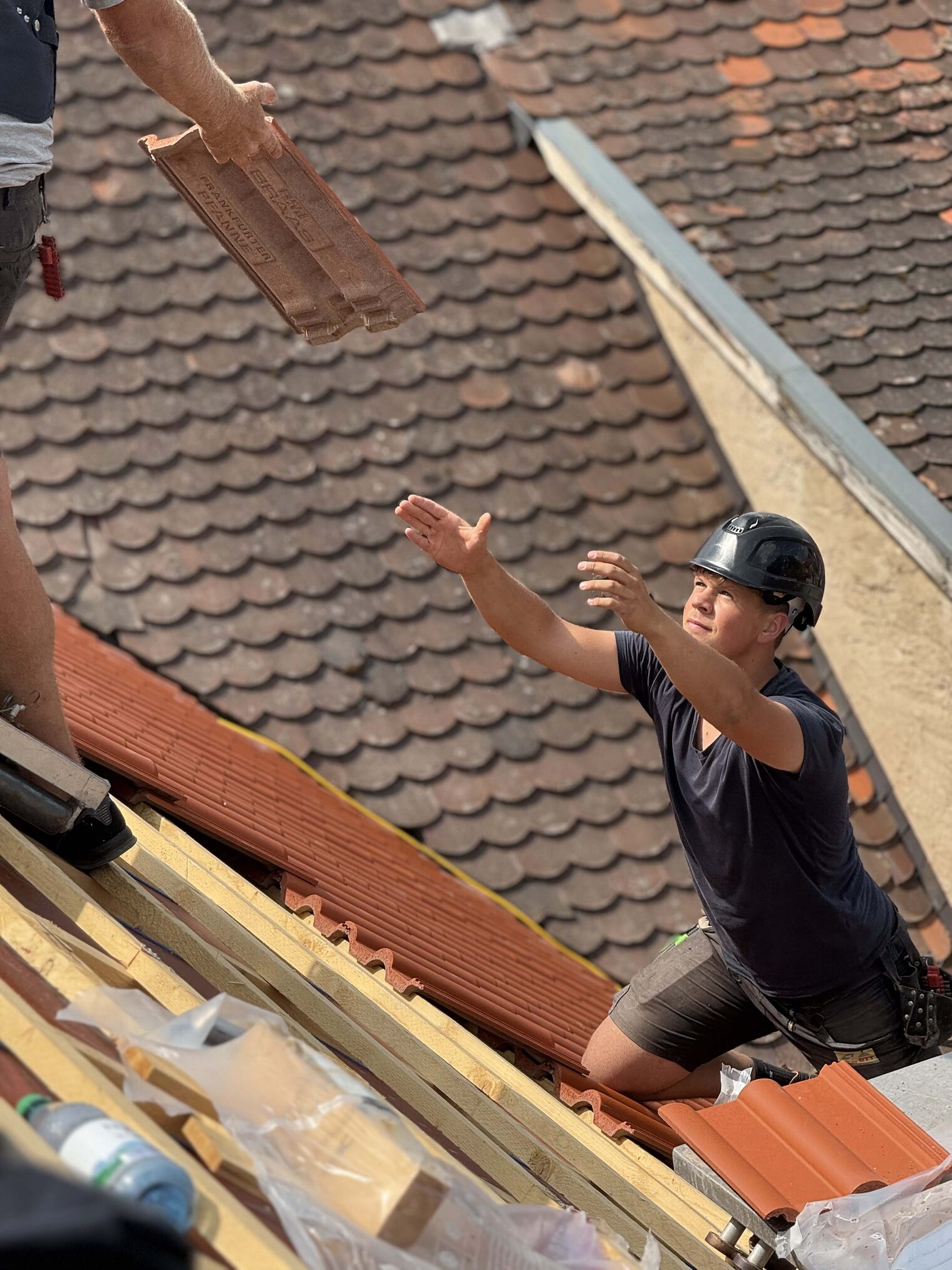 Dachdecker steht auf einem Haus und fängt Material