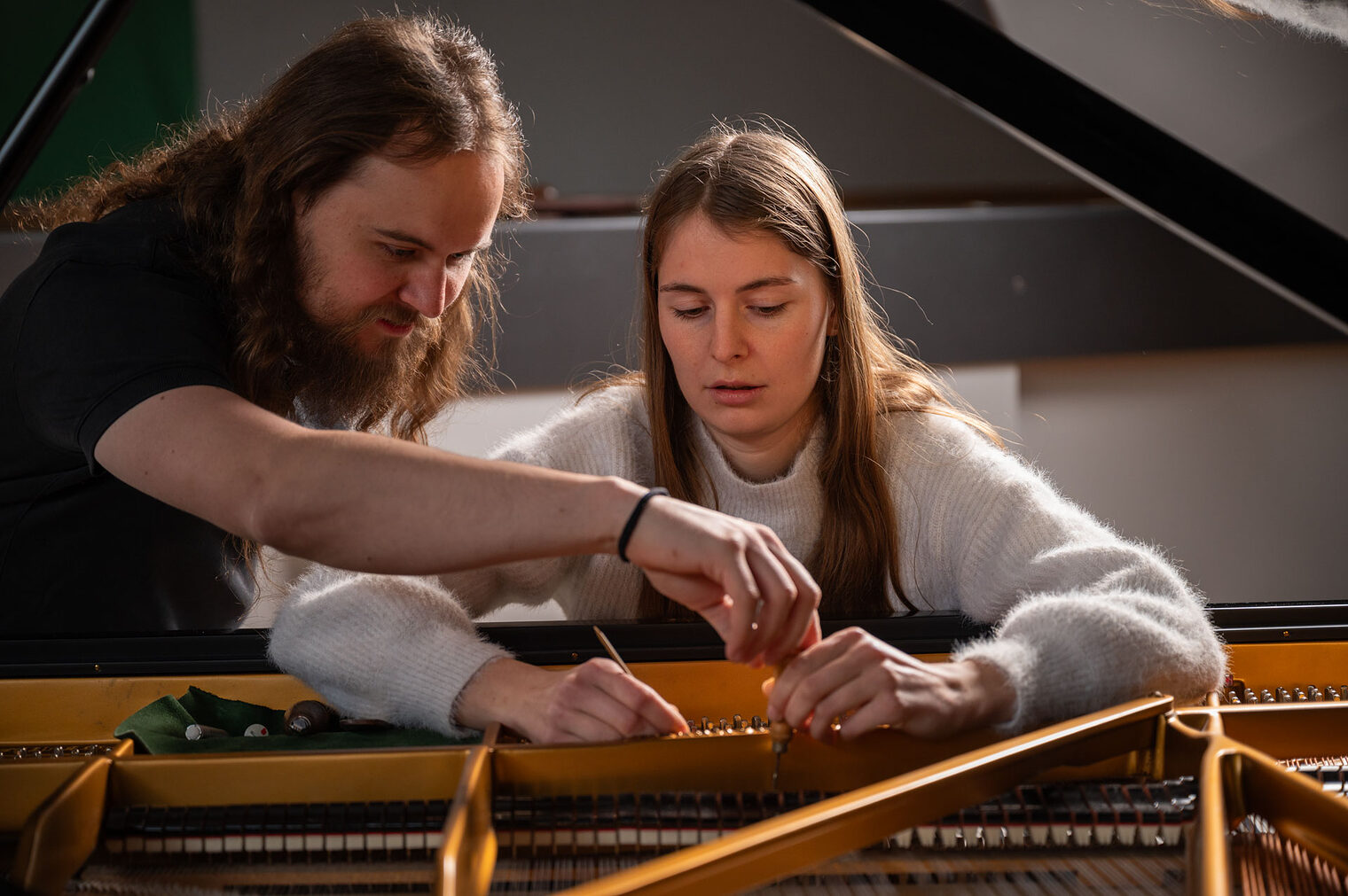 Mann und junge Frau schauen in einen offenen Flügel