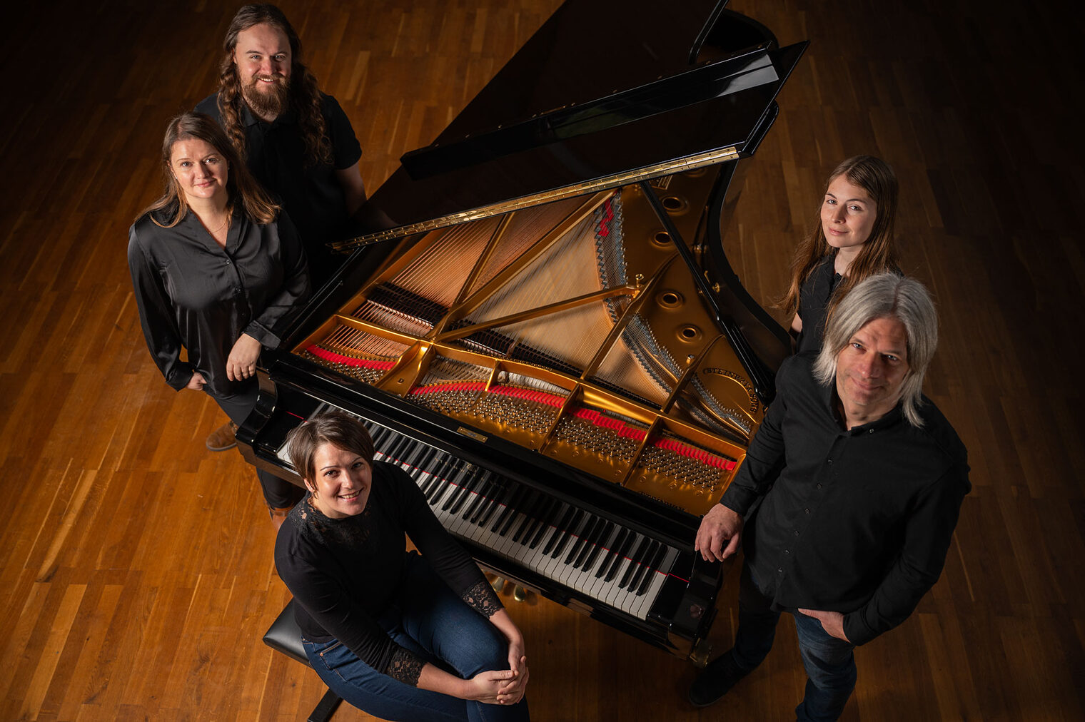 Gruppenbild: 5 Menschen um einen offenen Flügel, aus Vogelperspektive