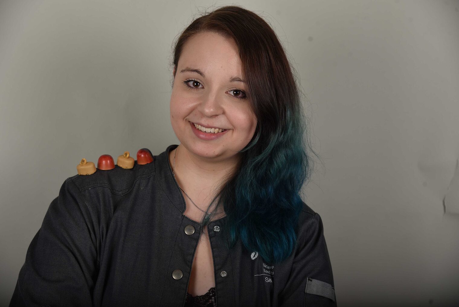 Frau lächelt in die Kamera, 4 Pralinien liegen auf ihrer Schulter