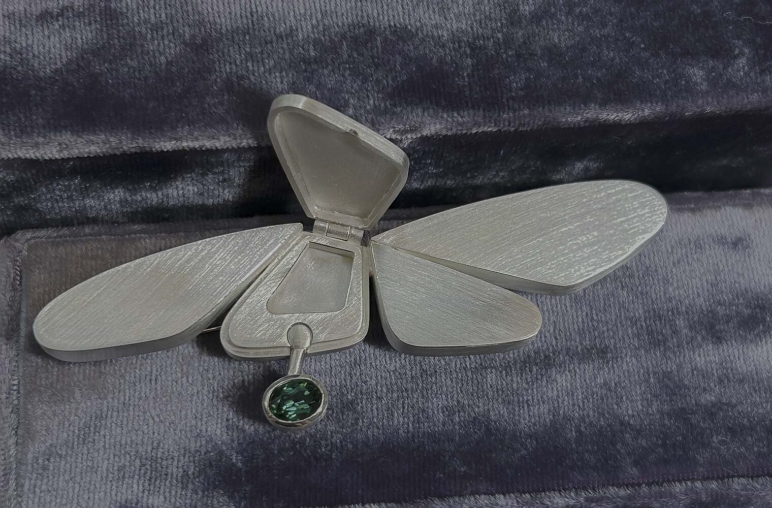 Schmuckstück mit Ähnlichkeit zu Schmetterling, grüner Stein eingefasst