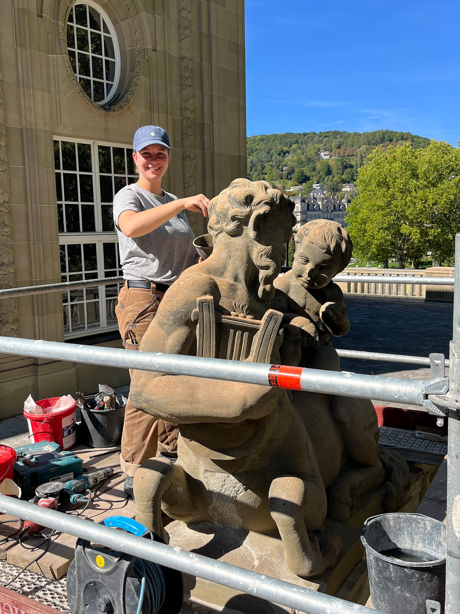 Steinmetzin auf Baustelle an einer Steinfigur