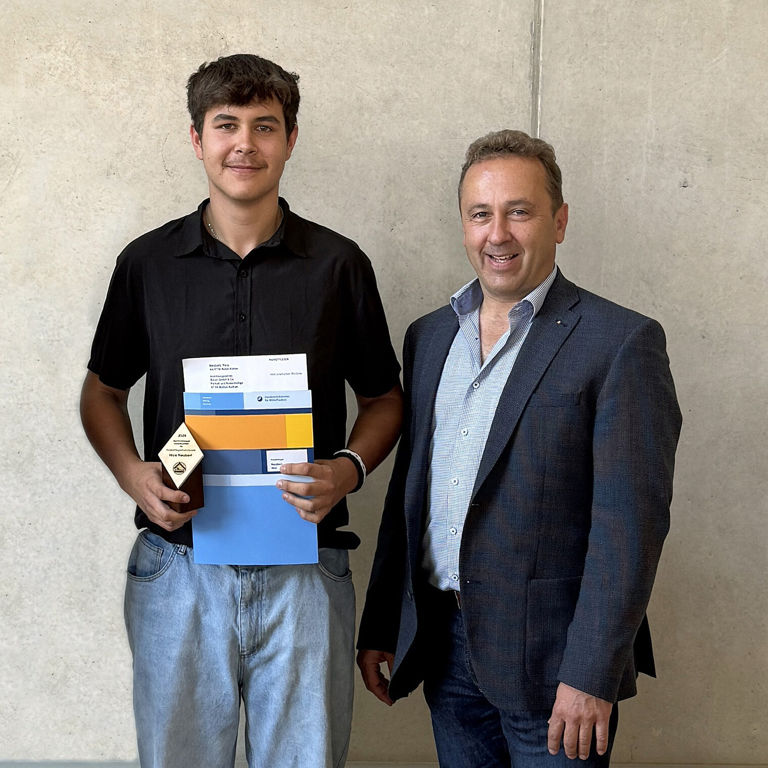 Zwei Personen, Azubi und Betriebsinhaber mit Auszechnungsurkunde