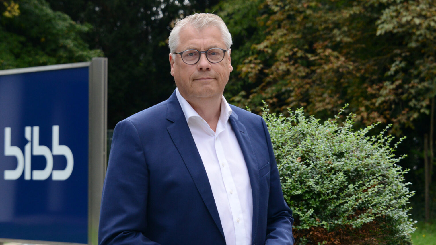 Porträtfoto draußen, im Hintergrund Stele mit Schriftzug "BIBB"