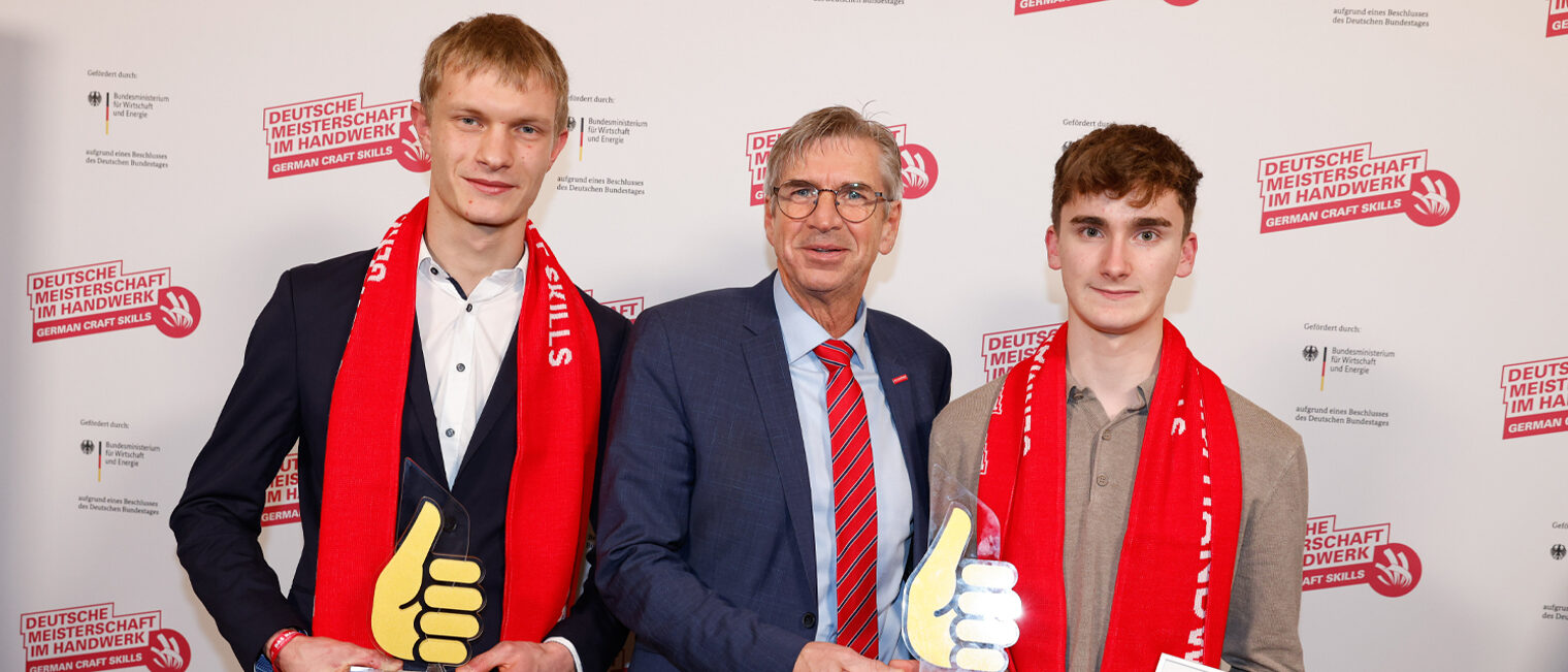 Gruppenfoto drei Personen vor Fotowand