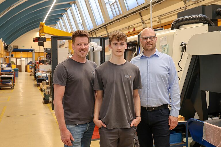 Gruppenfoto drei Personen in Produktionshalle