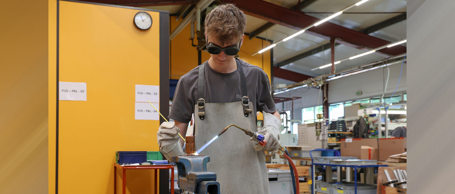 Junger Feinwerkmechaniker lötet ein Bauteil