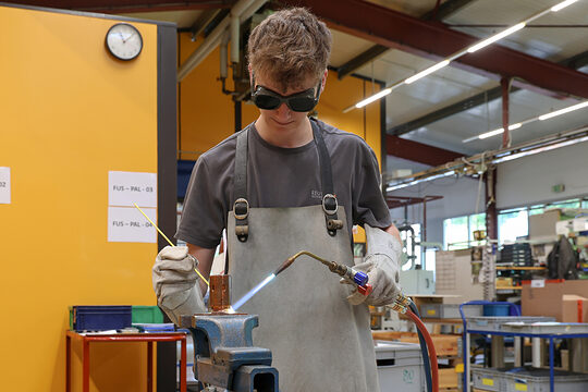 Junger Feinwerkmechaniker lötet ein Bauteil