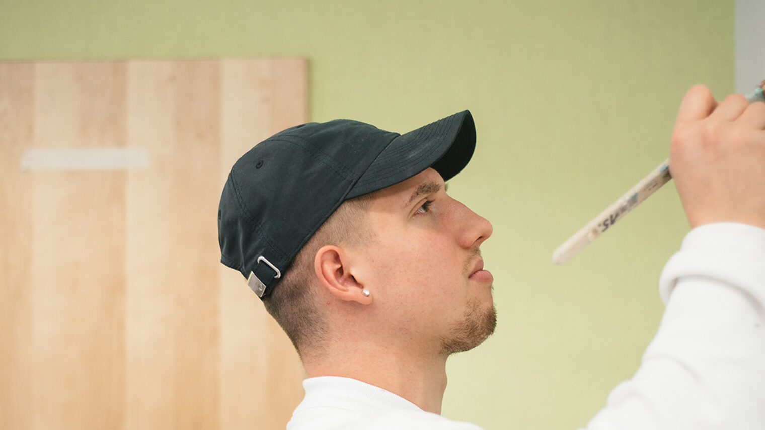 Maler- und Lackierer-Azubi streicht Wand bei der Überbetrieblichen Lehrlingsunterweisung im Bildungszentrum Aschaffenburg