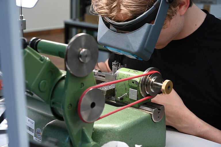 Uhrmachermeister Nahaufnahme mit Lupe arbeitet an Maschine